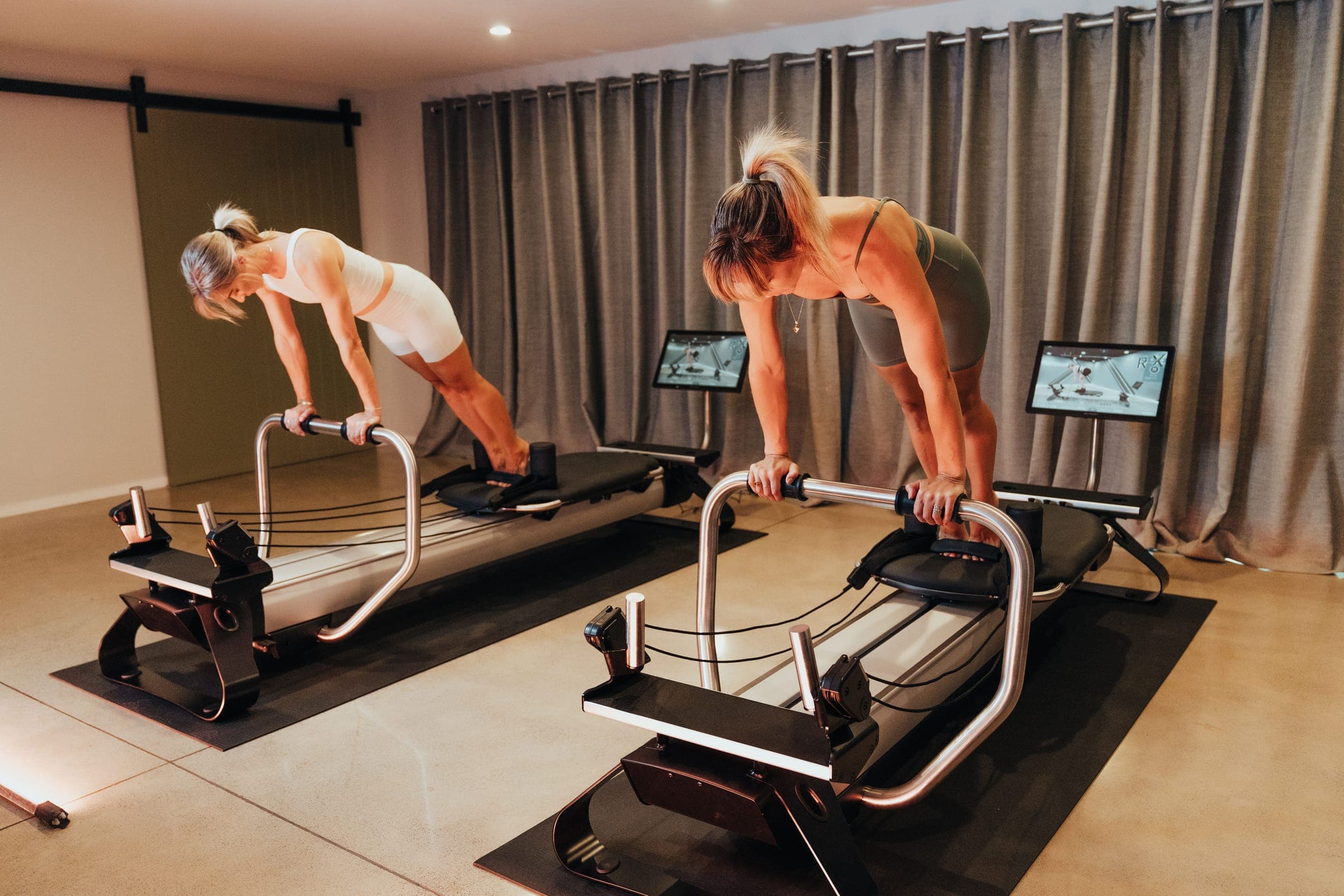 Dos mujeres entrenando en reformers de pilates en un estudio