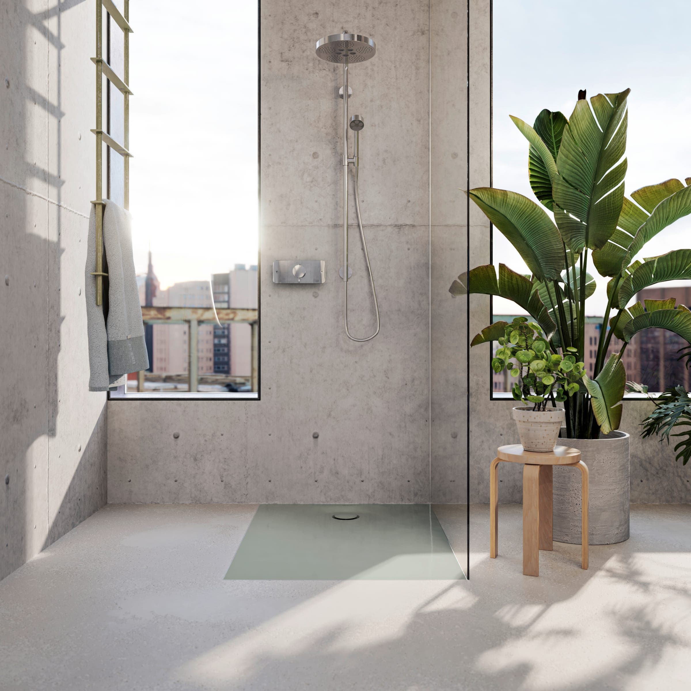 Regadera a ras de piso con plato verde claro, cancel de vidrio y regadera de techo y de mano en acero sobre un muro de concreto aparente; ventanas altas a la ciudad, un banco de madera con una maceta y plantas grandes.