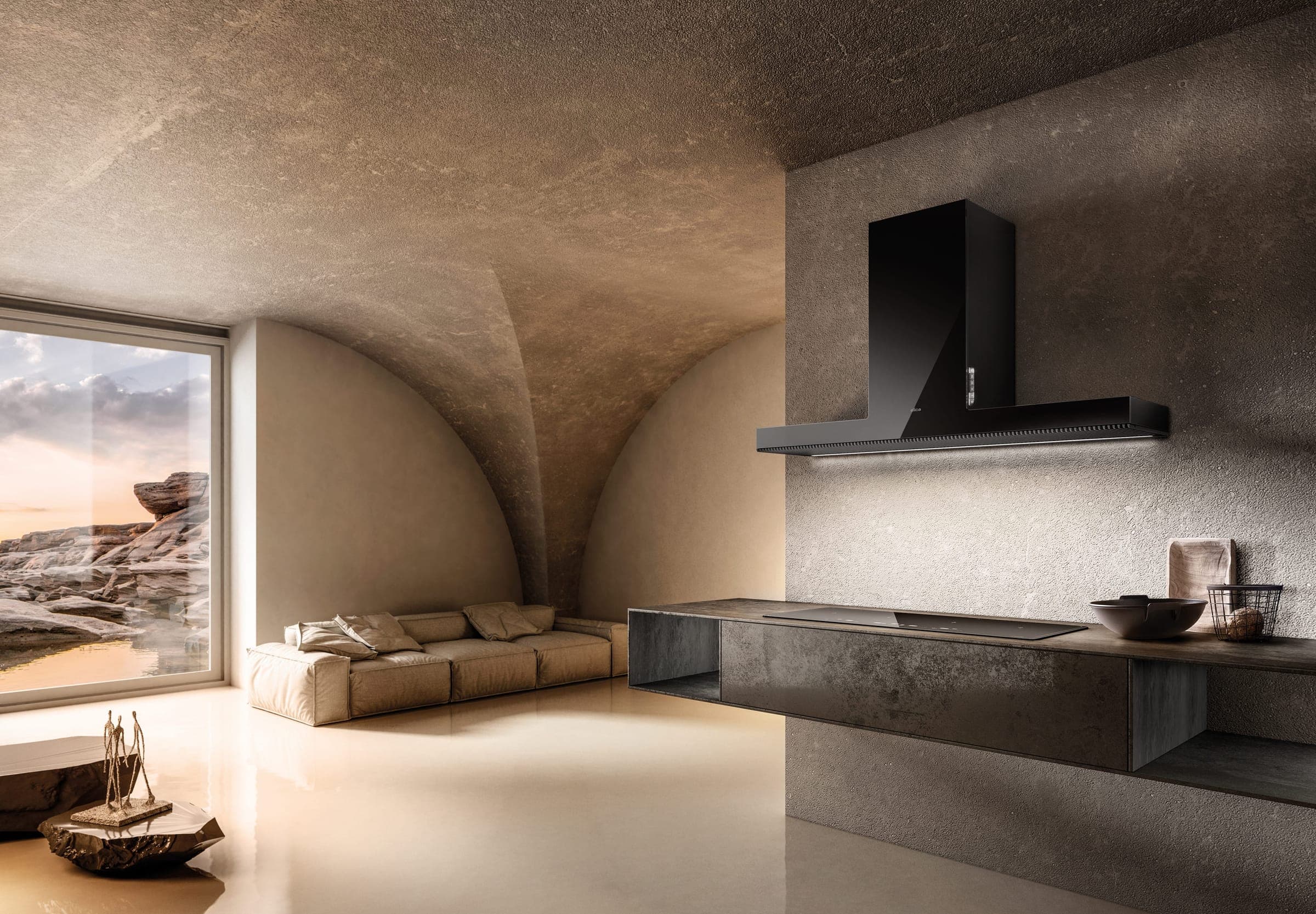 Campana de pared negra con chimenea sobre una barra flotante oscura con cubierta de cocción, en una estancia con bóvedas de piedra; un ventanal con una costa rocosa al atardecer, un sofá beige y una escultura sobre una roca.