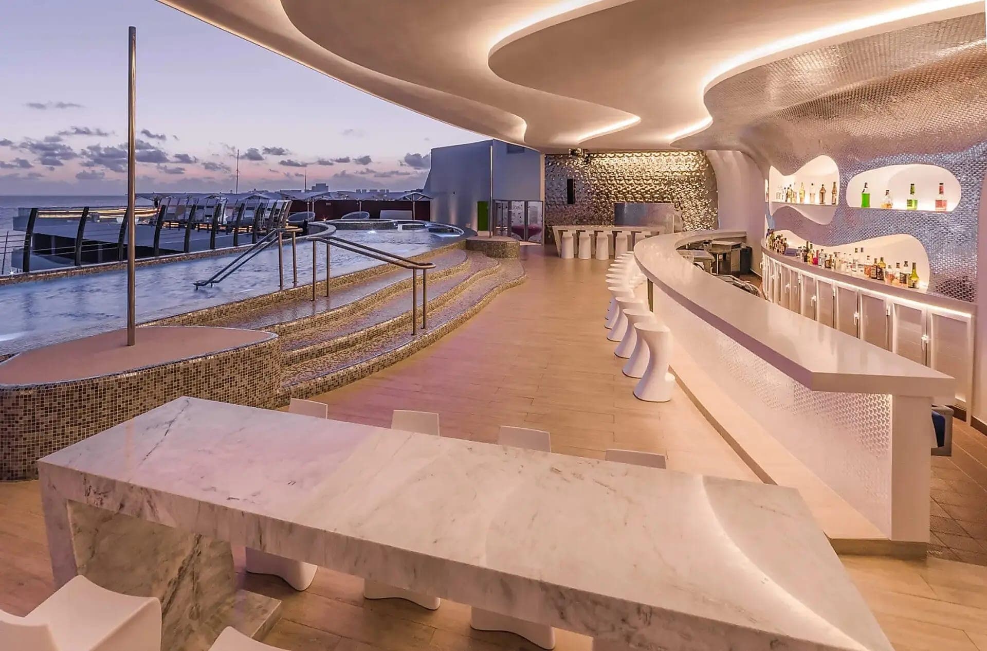 Bar en una azotea con barra y piso de mosaico dorado frente al mar