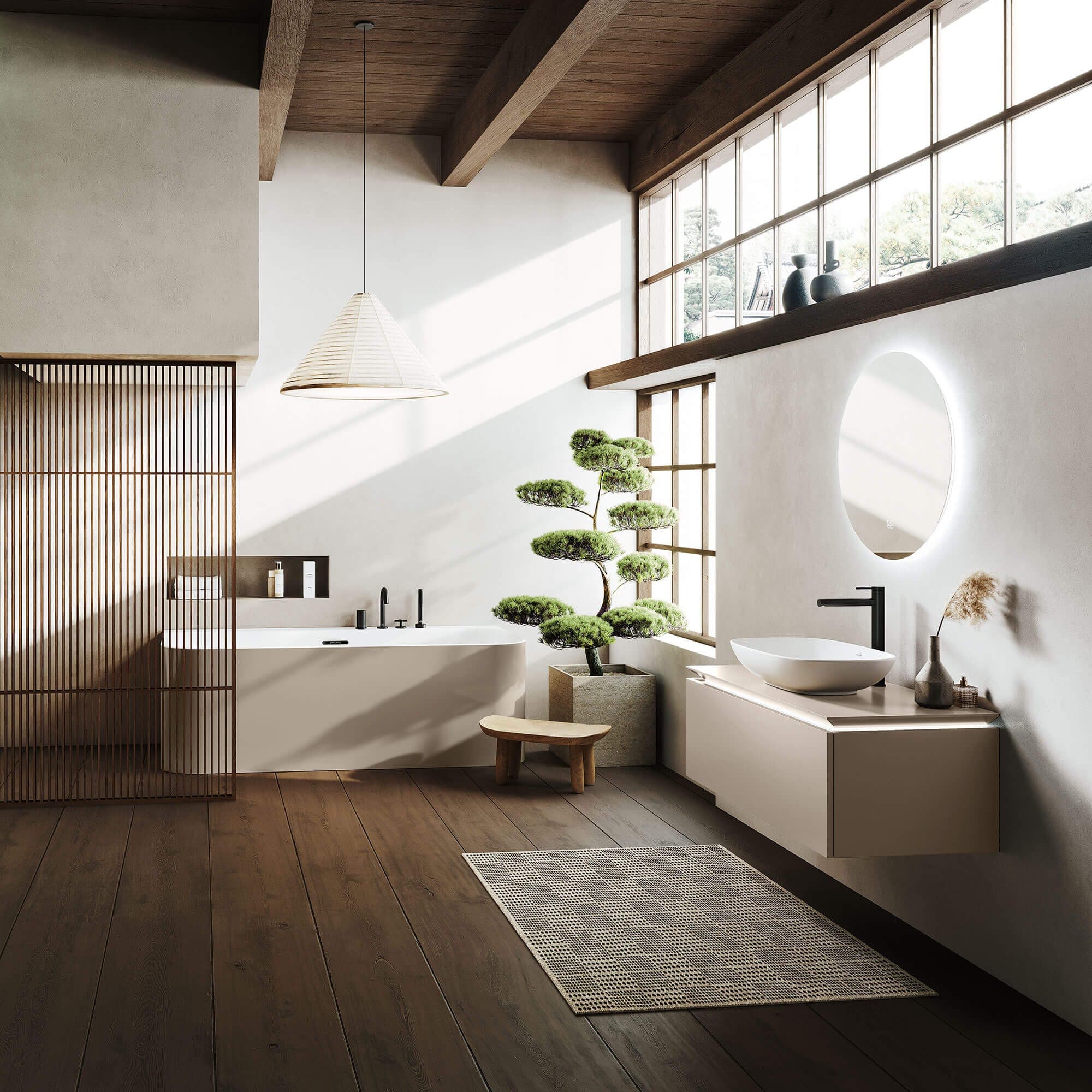 Baño de estilo japonés con vigas y piso de madera: tina blanca y beige de esquinas redondeadas junto a una celosía de madera, un bonsái, una banca baja y un lavabo blanco sobre mueble suspendido beige con grifo negro y espejo redondo iluminado.