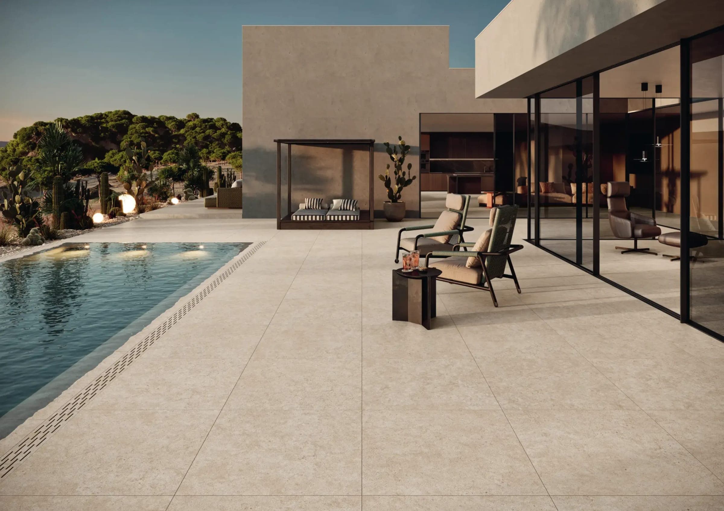 Terraza con alberca y piso de piedra clara al atardecer