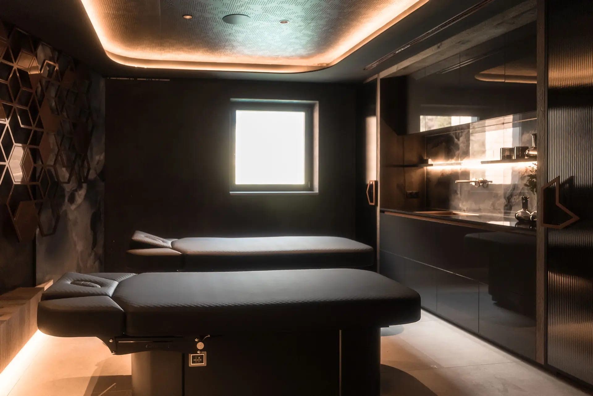 Cabina de spa en penumbra con dos mesas de tratamiento