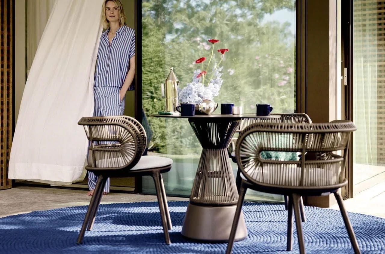 Comedor exterior con sillas tejidas sobre un tapete azul