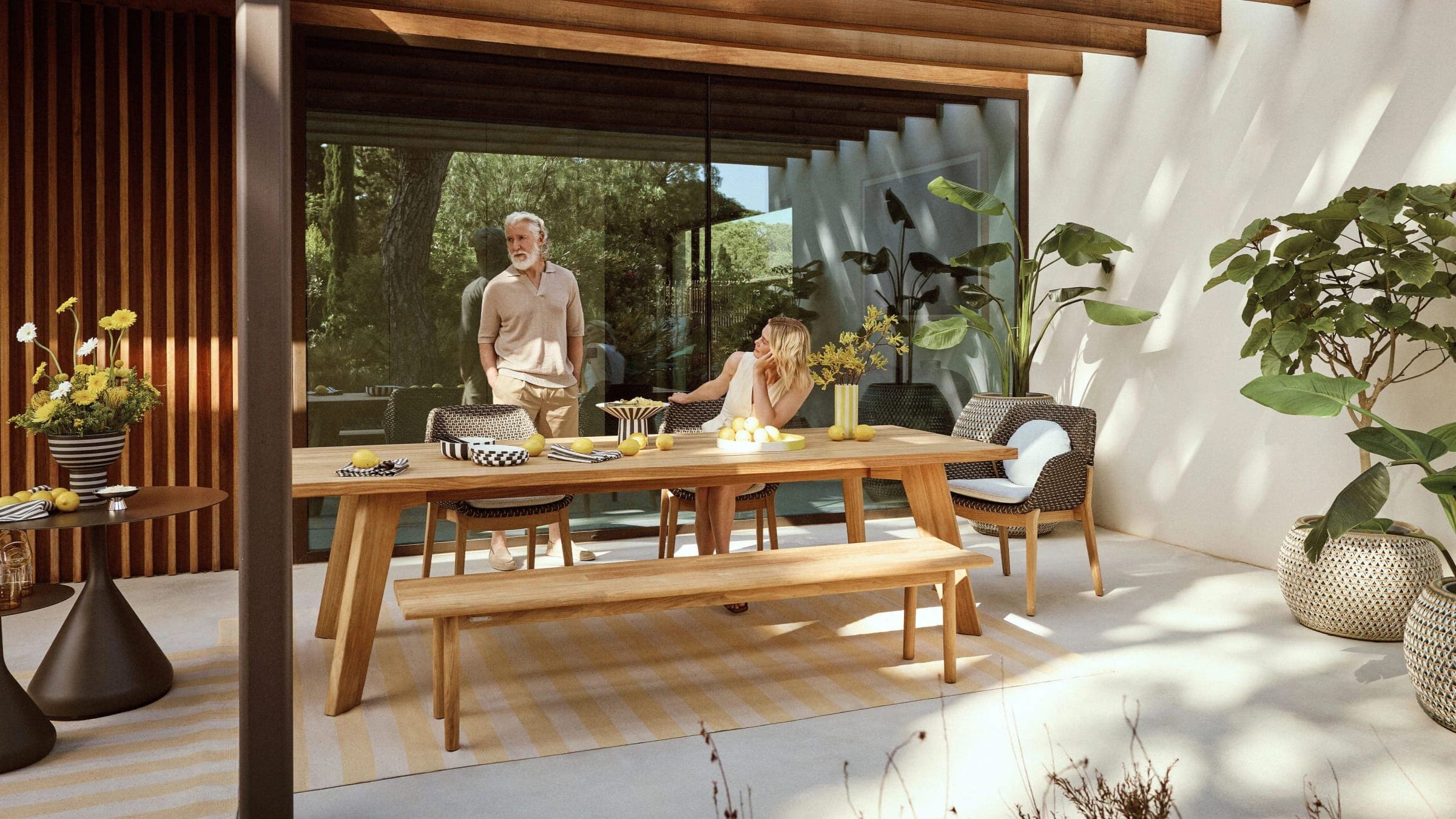 Comedor de madera bajo una pérgola con sillas tejidas