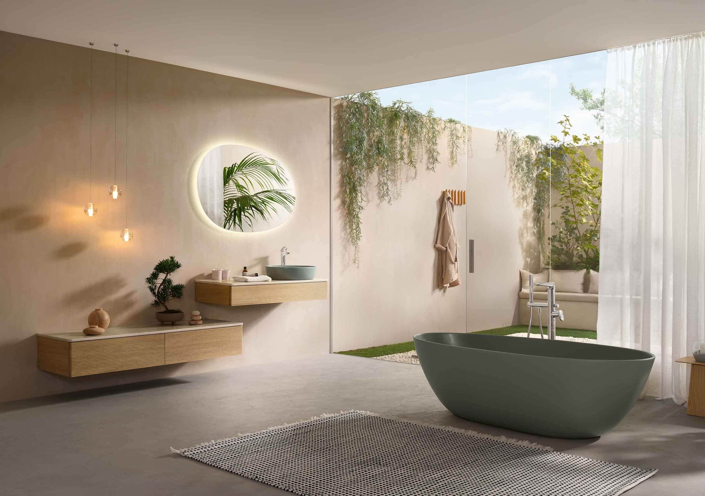 Baño abierto a un jardín con tina exenta verde y lavabo sobre una cubierta de madera
